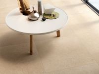 Scatto ravvicinato del pavimento della collezione Cover, con tavolino bianco ed alcuni arredi