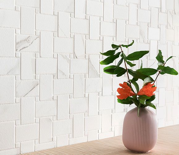 Immagine ravvicinata del rivestimento serie Charme colore Veined, con vaso di fiori posato davanti al rivestimento in gres con effetto marmo bianco e venature scure