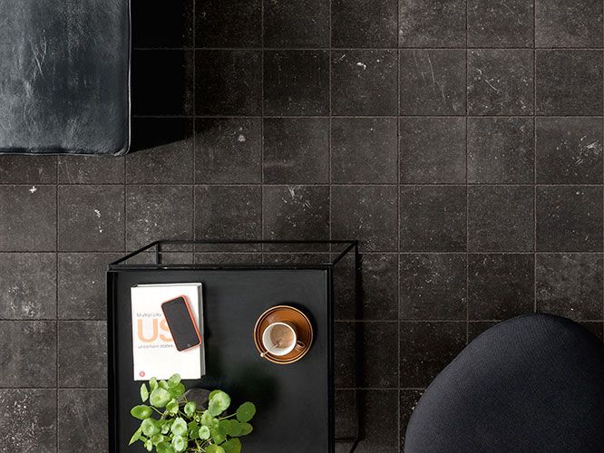 immagine zenitale della serie Concert, colore Black: pavimento con scorcio di poltrone e tavolino con oggetti