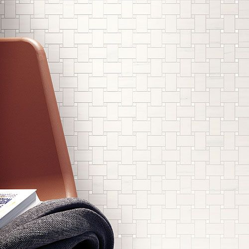 Immagine ravvicinata del rivestimento serie Charme colore Biancospino, con una poltroncina rossa davanti al rivestimento in gres con effetto marmo bianco.